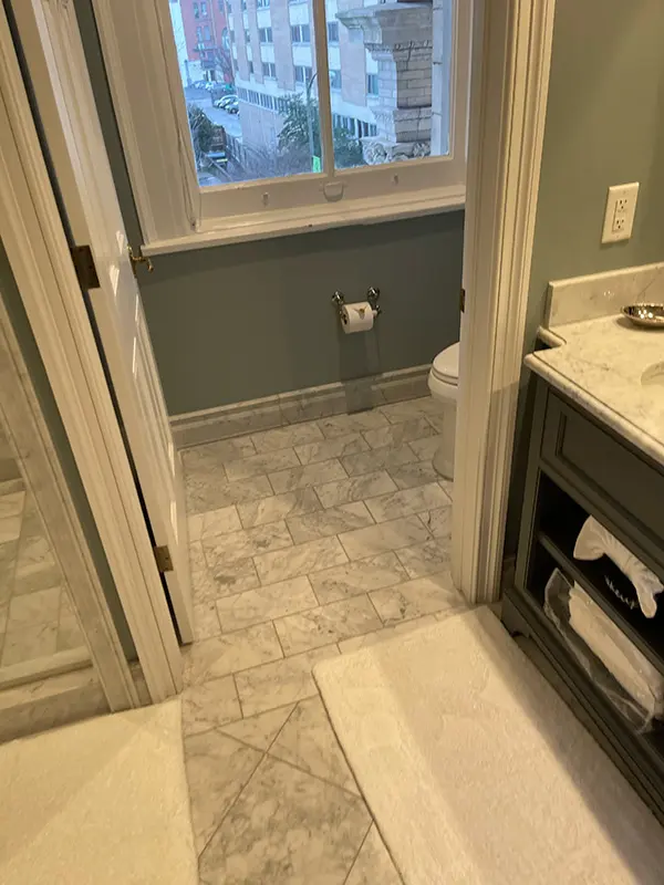 A bathroom interior showcasing dark gray walls, patterned tile flooring, a dark vanity, and a window letting in natural light.