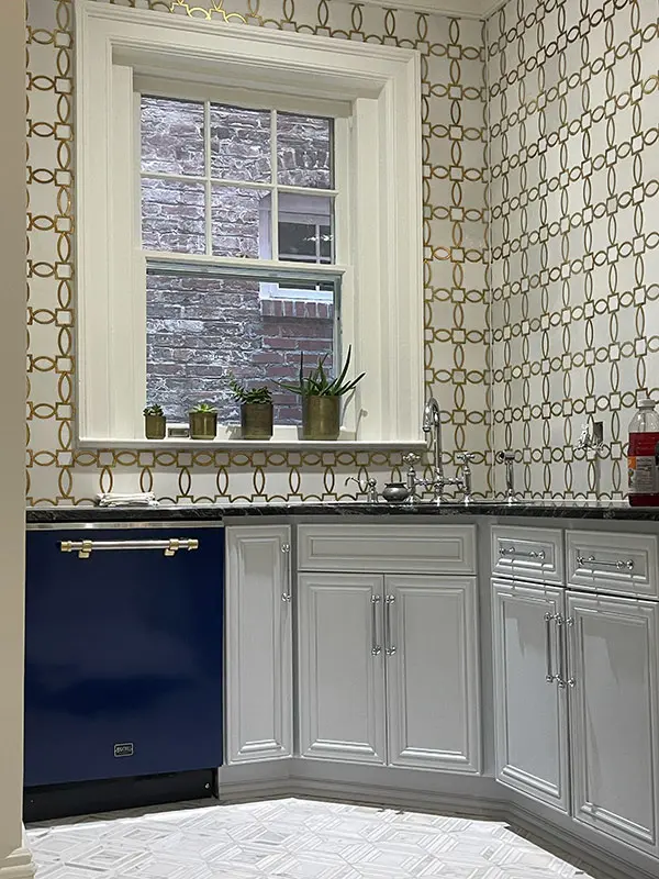 A modern kitchen remodel featuring a large window, intricate geometric tile backsplash, and sleek navy-blue lower cabinets.