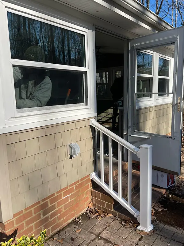 A close-up exterior view of a newly installed white-framed window above a brick foundation.